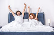 happy young couple stretching arms and waking up together in bedroom