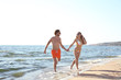 © New Africa - Happy young couple in beachwear running together on seashore