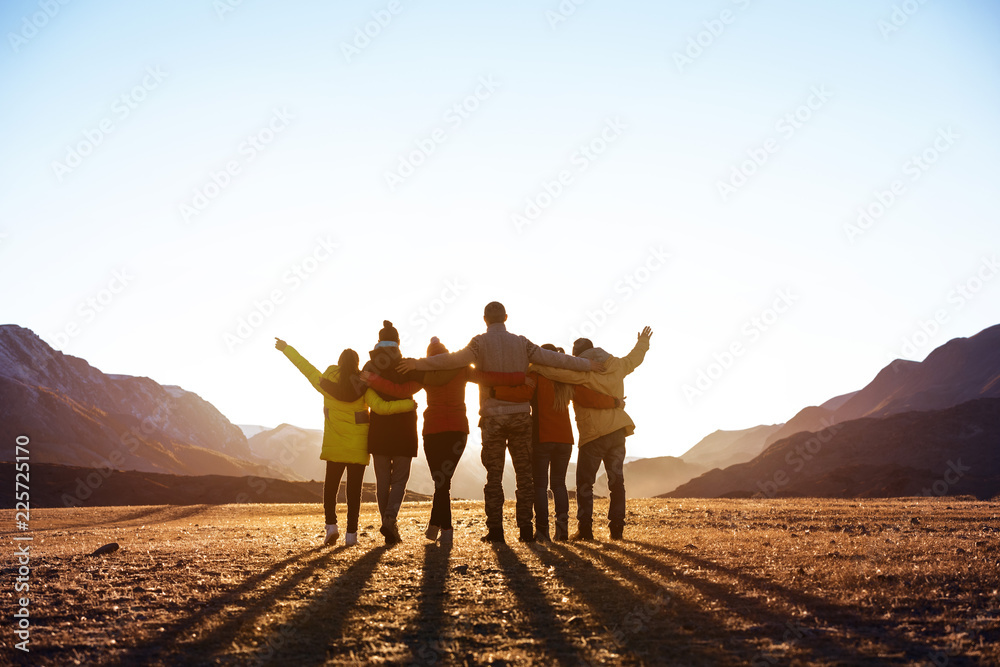 Group of friends against sunset mountains - obrazy, fototapety, plakaty 