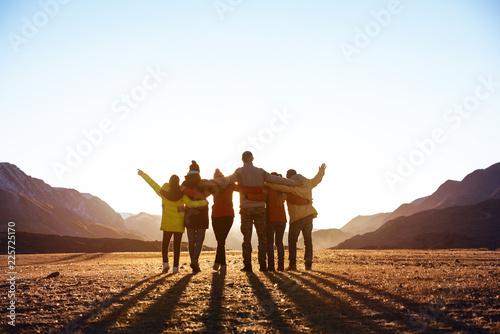 Group of friends against sunset mountains Poster Mural XXL
