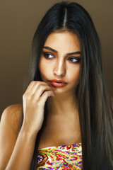 young pretty indian girl posing emotional on brown background, l