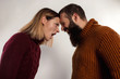 © oleg_ermak - Close-up portrait screaming couple looking at each other, dressed in warm knitted sweaters. Isolated gray background