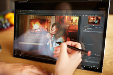 Fototapete - Freelancer retoucher woman works on convertible laptop computer with photo editing software using stylus. Photographer or designer digital image processing. 2 in 1 with touch screen in tent mode.