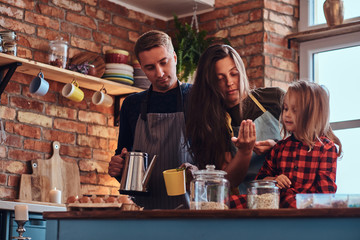 Wall Mural - Mom dad and little daughter together cooking breakfast in loft style kitchen.