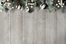 Top Border Of Silver Green Leaves And White Berries Over A Rustic Gray Wood Background. Top View With Copy Space.