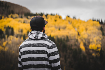 A man looking out into the distance of a mountain covered in fall foliage. 