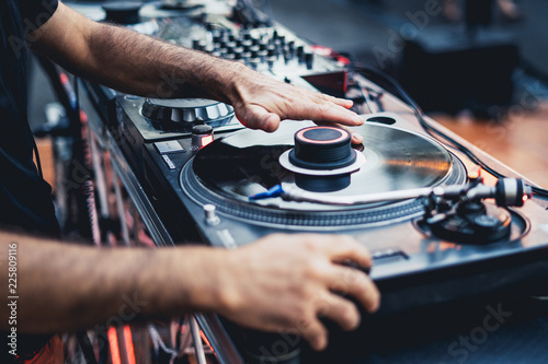 Fotografia  dj scratching a vinyl disc on a professional turntable, focus on the left hand scratching