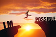 Man jumping over impossible or possible over cliff on sunset background