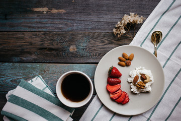 Wall Mural - a plate with cottage cheese, strawberries and nuts, a cup of coffee and towels on a wooden table, healthy food, breakfast