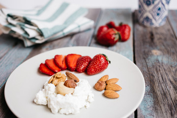 Wall Mural - a plate with cottage cheese, strawberries and nuts, a cup of coffee and towels on a wooden table, healthy food, breakfast