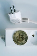Wall Mural - bitcoin coin lying on power strip extension cord with two empty sockets, cryptocurrency investing, e
