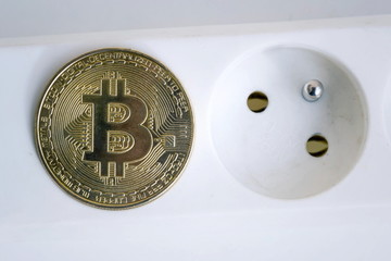 Wall Mural - bitcoin coin lying on power strip extension cord with two empty sockets, cryptocurrency investing, e