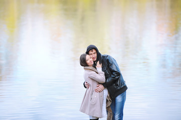 Beautiful loving couple standing by the autumn lake outdoors