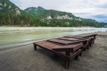 Wooden deck chairs at the fast mountain river