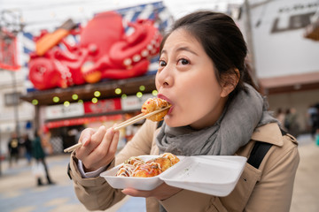 Wall Mural - woman is using chopsticks eating takoyaki