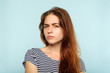 emotion face. suspicious thoughtful dubious distrustful woman. young beautiful brown haired girl portrait on blue background.
