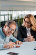 © LIGHTFIELD STUDIOS - smiling adult man and female car dealer playing with toy car in showroom