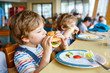 © Irina Schmidt - Cute healthy preschool boy eats hamburger sitting in school canteen