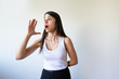 © KAMPUS - Emotional young woman screaming and holding hand according to sound direction. Shocked brunette girl calling. Announcement concept
