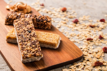 Mixed gluten free granola cereal energy bar with dried fruit & various nuts, gray concrete background. Healthy vegan super food, fitness dieting snack for sporty lifestyle. Top view, copy space.