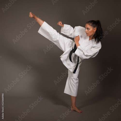 Photo Woman in white kimono kicks high in the air - a karate martial art girl