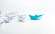 Leadership concept with blue paper ship leading among white on white background.