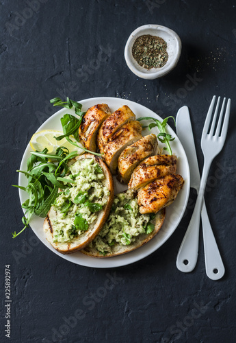 Fotografía Roasted chicken breast and avocado toast - healthy lunch on a dark background, t