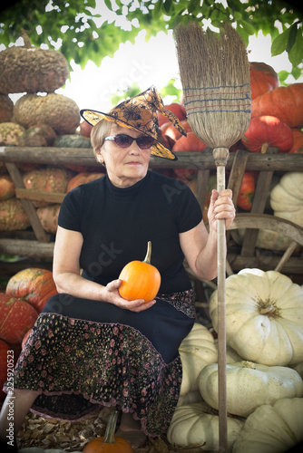 Fotografie, Obraz Friendly witch with broom on pumpkins background.