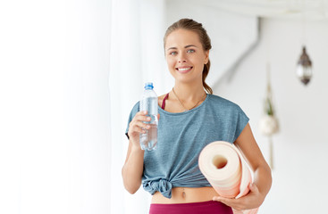 fitness, sport and healthy lifestyle concept - smiling young woman with bottle of water and exercise mat at yoga studio or gym