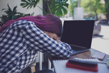 Young woman lying on her arms on the table in cafe in front of l