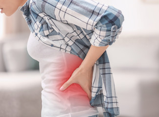 Canvas Print - Young woman suffering from back pain at home