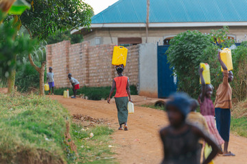 Wall Mural - woman carrying water can in Uganda, Africa