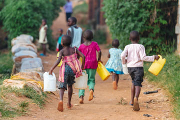 children carrying water cans in uganda, africa