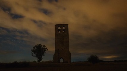 Wall Mural - the milky way moving across the night sky and an ancient castle tower in a partly cloudy summer nigh