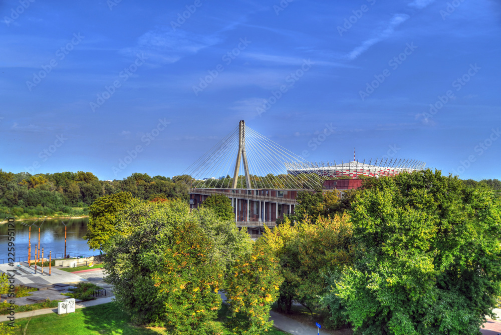 Colorful HDR image of gardens and the Swietokrzyski Bridge with the PGE Narodowy National Stadium in Praga District, Warsaw, Poland - obrazy, fototapety, plakaty 
