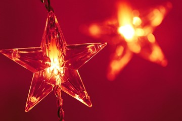 Shining garland festive background. Christmas background.star glowing on a blurred warm red background