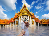 Women tourists holding man's hand and leading him to Wat Benchamabophit or the Marble Temple in Bangkok, Thailand.