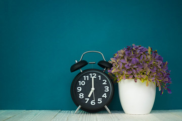 Wall Mural - Little decorative tree and flower bouquet in white vase with vintage alarm clock on wooden table with copy space.