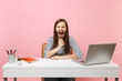 © ViDi Studio - Angry woman in casual clothes screaming holding magnifying glass sit work at white desk with contemporary pc laptop isolated on pastel pink background. Achievement business career concept. Copy space.