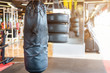 Black punching bag hanging in Abstract blur of defocused boxing gym interior and fitness health club with sports exercise equipment Gym blur background.