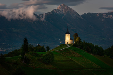 Church on the hill at night.Beautiful scenery at Jamnik, Slovenia. Panoramic view of the Alps behind the church.