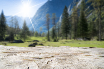 Empty wooden table with blurred mountain outdoor background. Ready for product montage.