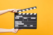 © ViDi Studio - Close up female holding in hand classic director clear empty black film making clapperboard isolated on trending yellow orange background. Cinematography production concept. Copy space for advertising