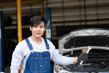 Wall Mural - Reliable auto mechanic showing wrench  in a modern automobile repair shop