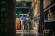 © Dusan Petkovic - Picture of two business man standing in warehouse with helmets on their heads and celebrating great news about their business. Standing in big warehouse and looking happy and satisfied.