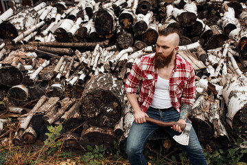 Wall Mural - bearded mohawk Man sitting on firewoods. Woodcutter with axe resting after work