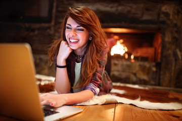 Young woman working on laptop while lying on the floor