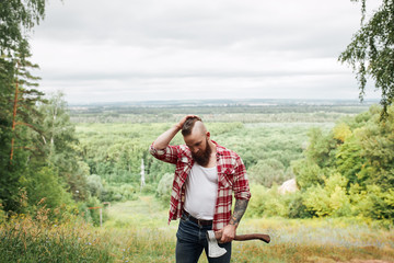 Wall Mural - bearded mohawk lumberjack worker standing in forest with axe