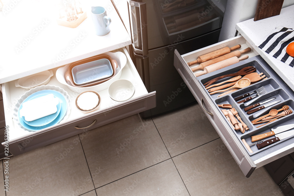 Set of clean kitchenware and utensils in drawers