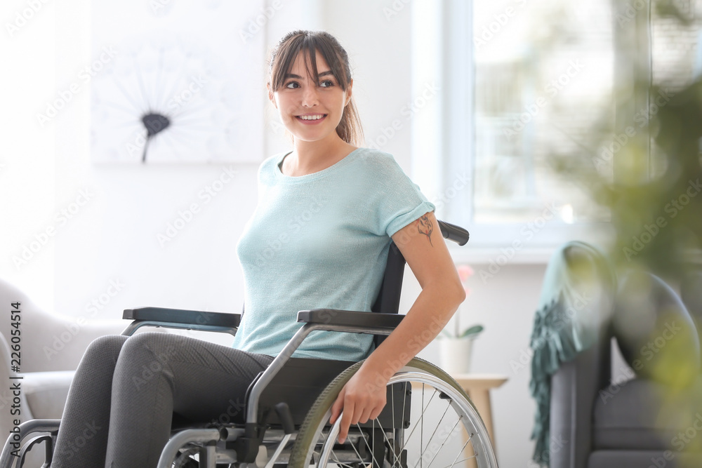 Happy young woman in wheelchair at home - obrazy, fototapety, plakaty 